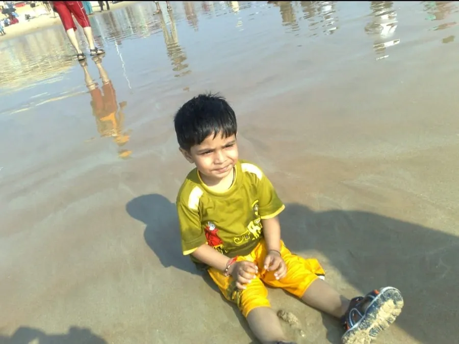 Hardik as a small kid sitting on a beach